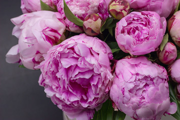 Pink peonies in a hat box on a dark background.