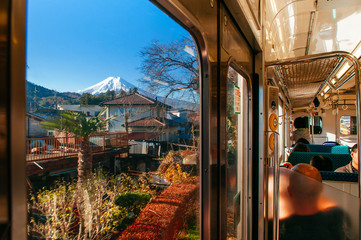 Snow covered Mount Fuji and local town along train route seen through window in Shimoyoshida -...