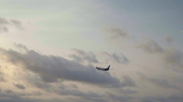 Small jet airplane is taking off in sunset with blue sky and clouds