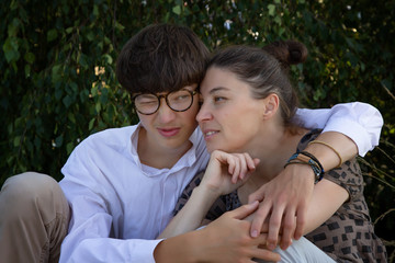 family relationships, middle-aged woman, mother, is talking with her student son. Young handsome man in a white shirt and glasses.
