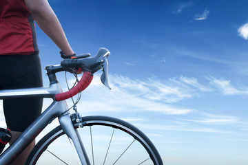 Fototapeta na wymiar One cheerful cycling guy standing with his bike on blue sky background