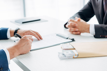 cropped view of man gesturing near business partner holding pen and contract