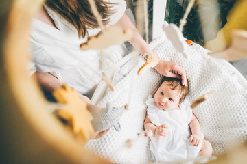 Funny two month old baby girl lying on the bad. Mother stroking daughter. High angle view of...