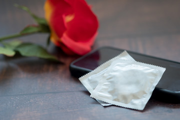 Condom and red roses on wooden table. Valentine concept