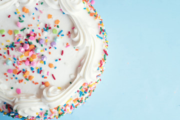 Top view of a cake with colorful sprinkles on a light blue background - Powered by Adobe