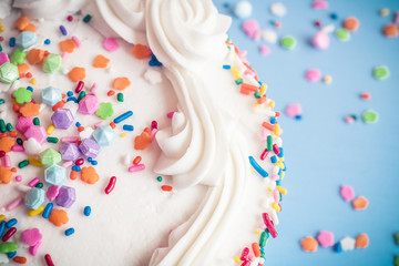 Up close view of a cake with colorful sprinkles on a light blue background