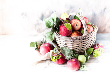 Red apples in a wicker basket on a wooden table, blurred background