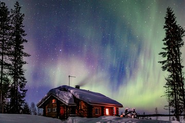 Polar arctic Northern lights Aurora Borealis activity over wooden cottage in winter Finland, Lapland