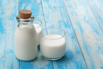 A bottle of milk and glass of milk on a blue wooden table, healthy dairy products concept