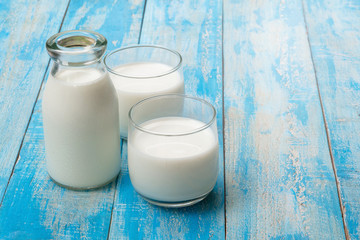 A bottle of milk and glass of milk on a blue wooden table, healthy dairy products concept