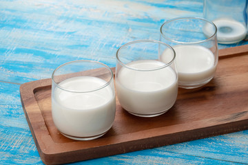A bottle of milk and glass of milk on a blue wooden table, healthy dairy products concept
