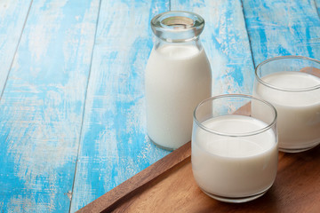 A bottle of milk and glass of milk on a blue wooden table, healthy dairy products concept