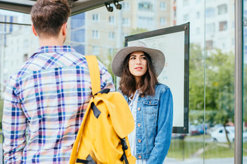 Guy at bus stop looking at girl next to him, waiting for tram, love at first sight feelings concept.
