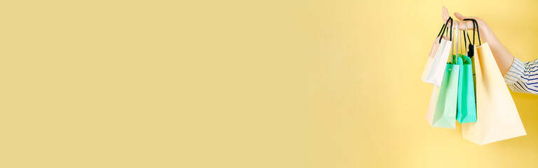 web banner mid season sale and shopping activity from hand hold the shopping bag with copy space and yellow vintage background