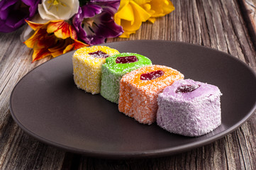 Closeup view of assortment turkish delight in dark trandy plate on wooden background.