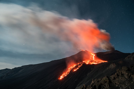 Eruption Volcano Etna with smoke and lava flow at night