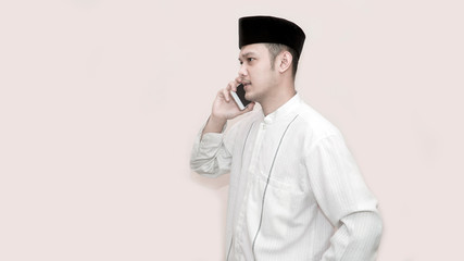 side view portrait of an asian muslim man using smartphone taking a call