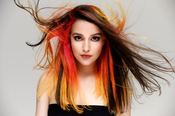 Fototapeta premium Studio portrait of a model with perfect makeup and colored hair on a white background. Beautiful female face of a pretty girl. Perfect makeup. Skin care. Fashionable cosmetics.
