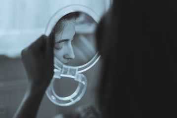 Young depressed woman cannot stand her self reflection in the mirror