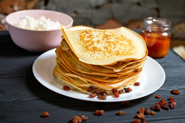 Crepes on a wooden table with honey and raisins.