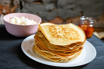 Crepes on a wooden table with honey and raisins.