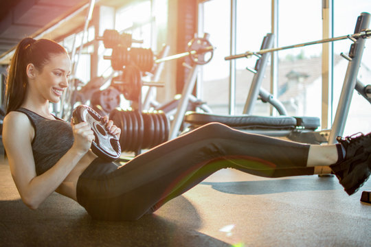 Young Sporty Woman Doing Situps With Weights In Gym