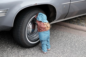 Puppe mit blauen Jeans und Hut beim Radwechsel eines amerikanischen Auto der Siebzigerjahre im...