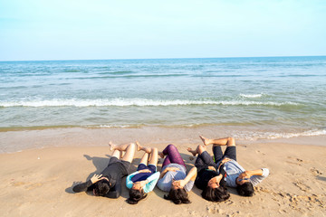 Asian teenager is sleepping by the beach with friends. A group of friends are sleepping on the beach to play in the sea. Travel with friends concept.