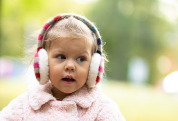 Beautiful joyful little girl looking aside in the autumn park