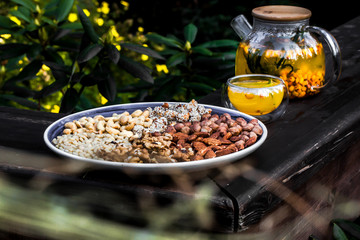 Plate with nuts and background with teapot on nature