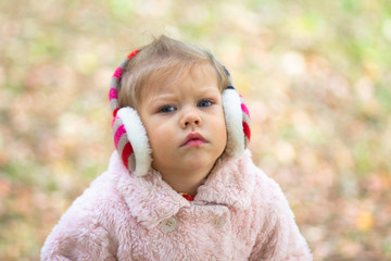 Beautiful serious little girl looking at camera in the autumn park