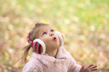 Beautiful surprised lttle girl looking up in the autumn park