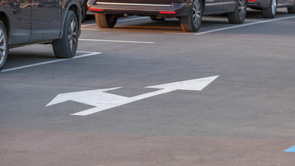 Traffic signals painted on the parking. Road marking with two - directions arrow. Full Parking lots with cars, driving direction. Marking on asphalt road.