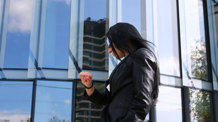 Portrait of young beautiful business woman (student) in suit, future glasses, smiling, successful looking at sides, with skyscraper background. Concept: New business, Communication, Future,  Manager.