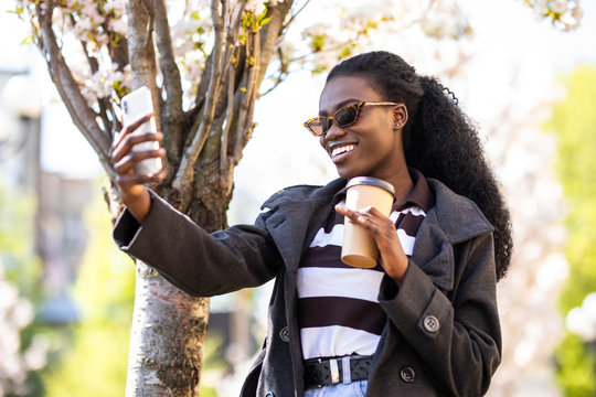 Smiling Young African Woman Using Video Call Talk With Colleague While Walking In The Street