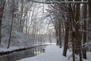 Deep snowy forest road at a stream in winter