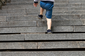 Fototapeta na wymiar Boy climbing stairs stone - symbol of success