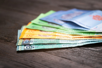 Various type of Malaysia Currency (MYR): Stack of Ringgit Malaysia bank note on dark brown a wooden table background. (There are one, five, twenty and fifty)