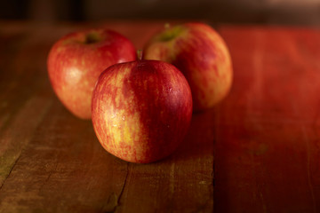 Red apples on wooden table. Dark food.