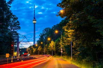 Deutschland, Stuttgarter Stadtfernsehturm, Fernsehturm in magischer Dämmerungsatmosphäre nach Sonnenuntergang hinter Straße mit Verkehr im Wald © Simon