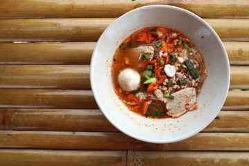 Close up Tom Yum Noodles Served in a round white bowl Put on a bamboo mat