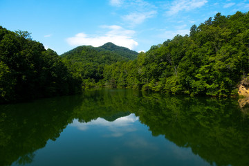 Fototapeta na wymiar Blue sky and clouds reflected in the lake water in a cove
