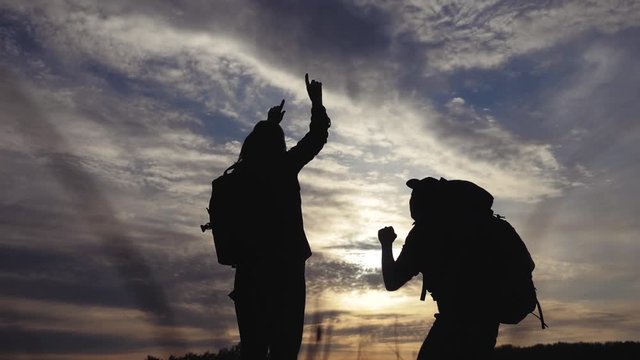 teamwork business journey concept win. couple man and woman jump joy hold lifestyle hand silhouette. slow motion video. teamwork couple husband and wife hikers sunshine sunset tourists go on a nature