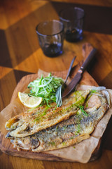 delicious golden batter deep fried fish fillets, served on white plate on old dark wooden worktop, view from above, blank space for text left