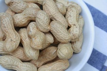 Peanuts in nutshell in a bowl on wooden table