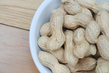 Peanuts in nutshell in a bowl on wooden table