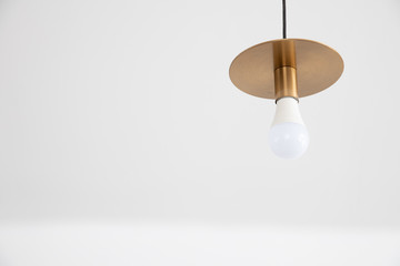 closeup view of retro gold lamp and white bulb hanging from ceiling with copyspace.