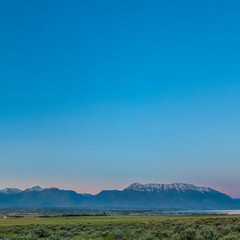 Obraz premium Square frame Scenic panoramic view of the valley lake and snow peaked mountain under blue sky