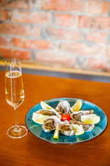 fresh and delicious oysters with lemon and a glass of champagne lie on a plate in a restaurant
