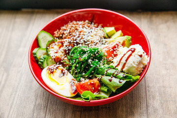 delicious and appetizing salad egg, tomato, spinach, cucumber, cheese, cilantro, lies on a red plate in a restaurant